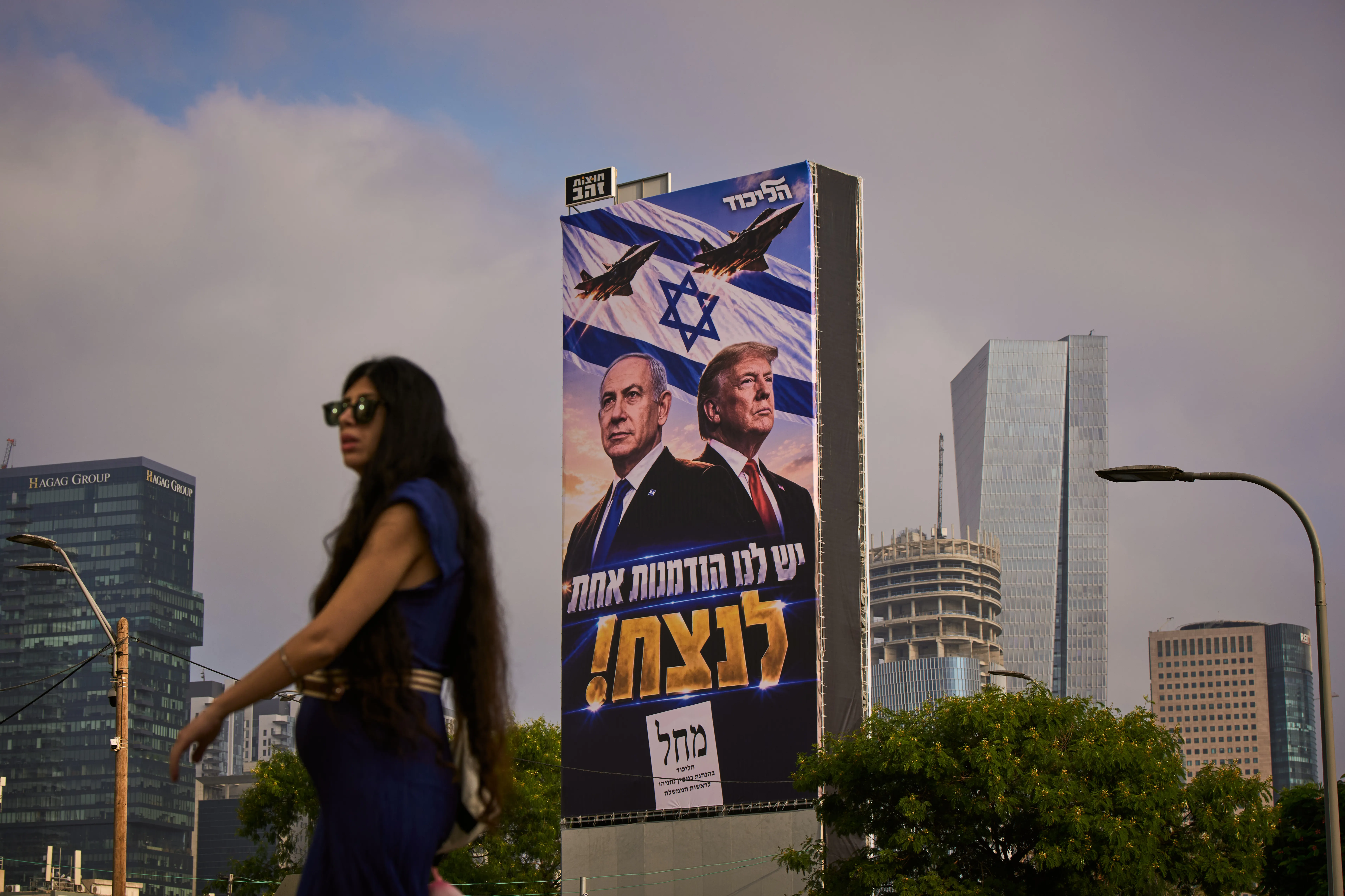 A woman walks past a Likud Party campaign billboard featuring President Trump and Israeli Prime Minister Benjamin Netanyahu, with a Hebrew message reading, "We have one opportunity to win," in Tel Aviv, Israel, on Monday.