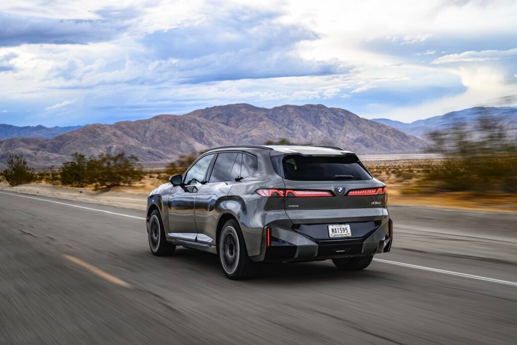 A BMW iX5 drives away from the camera
