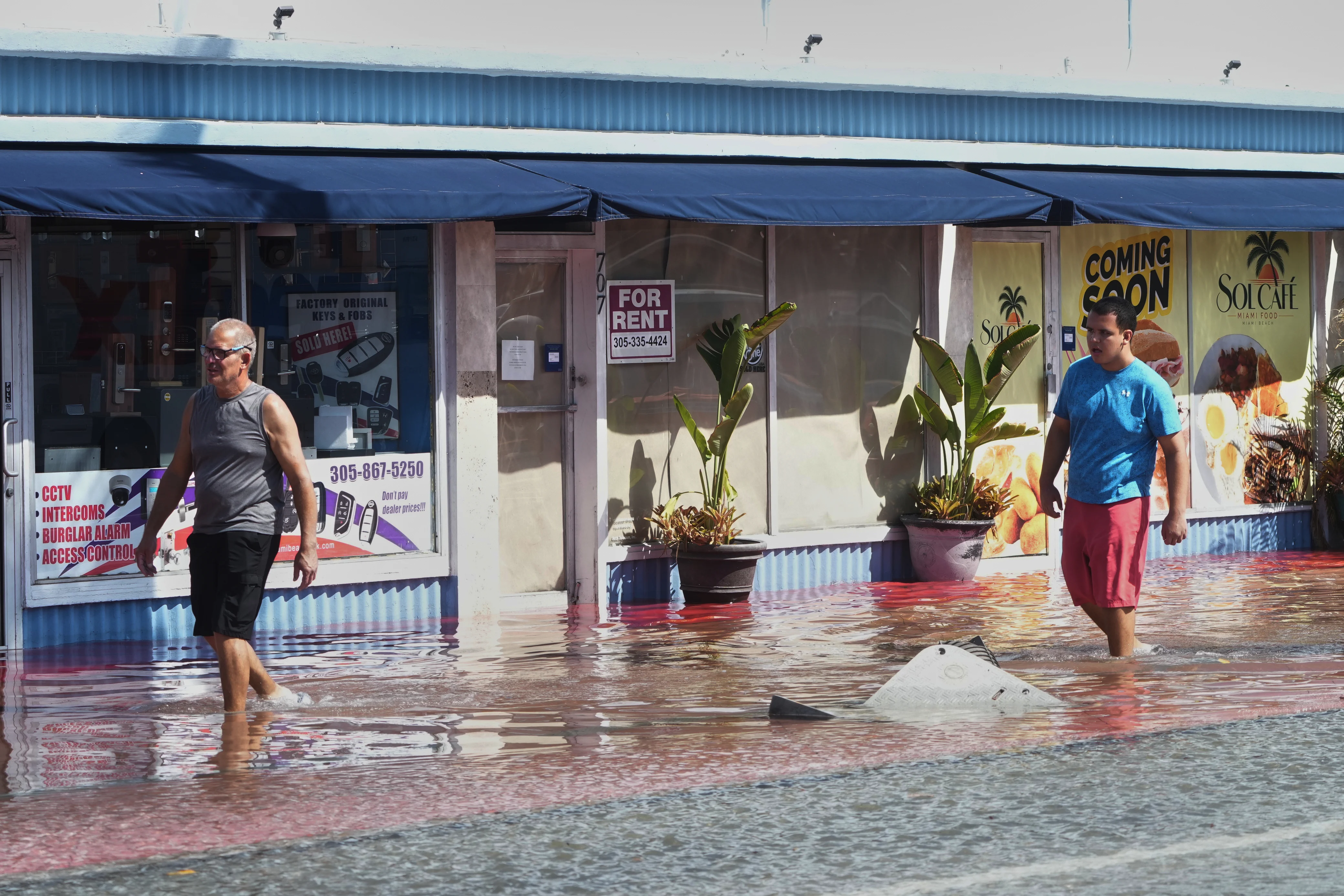 Pedestrians walk through a flooded street caused by king tides and heavy rain Wednesday, Oct. 28, 2026, in North Bay Village, Fla.
