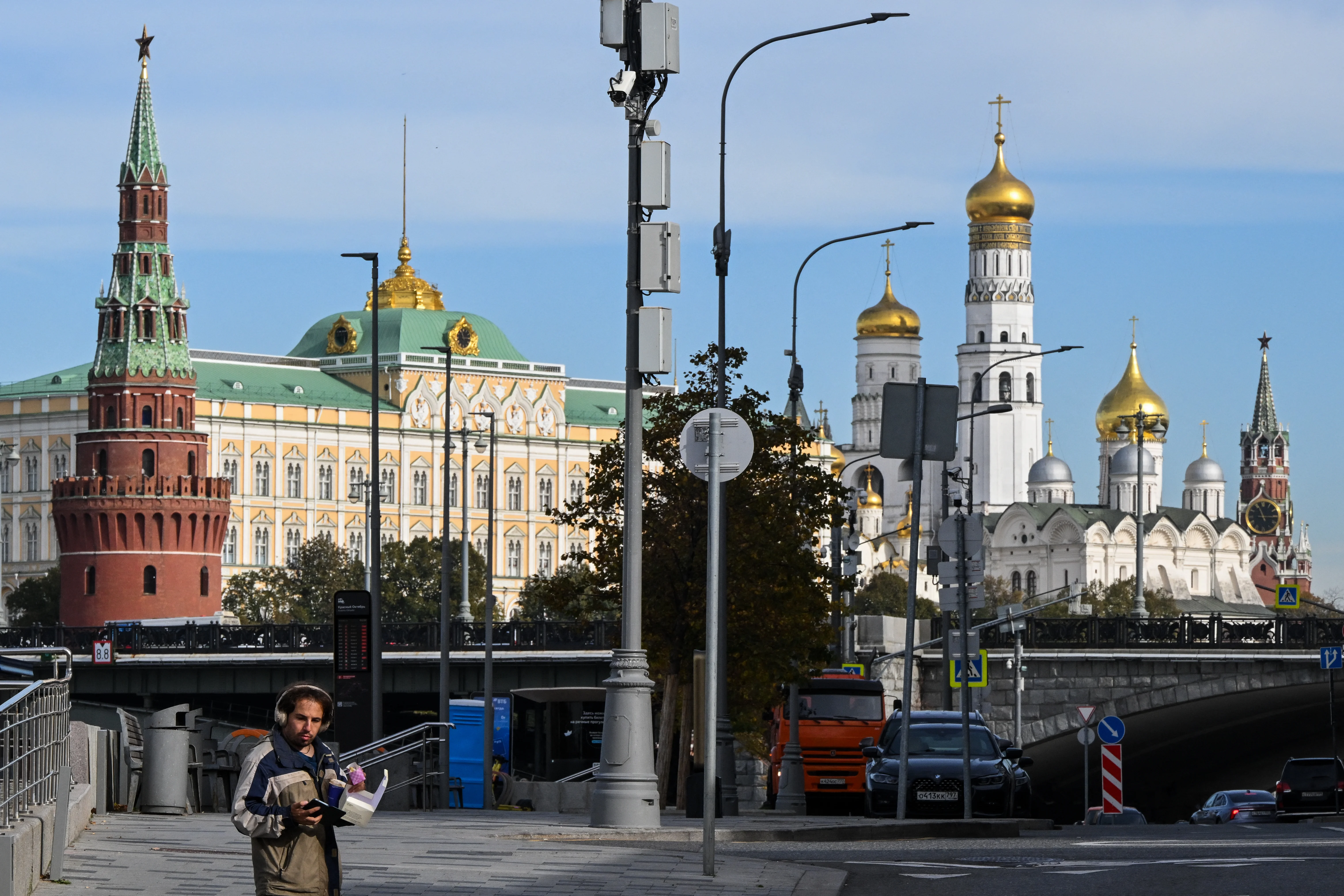 A pedestrian looks at his smartphone on an embankment with the Kremlin in the background in central Moscow on Oct. 8, 2026. Researchers who track online influence operations say Kremlin-backed groups are renewing tactics they