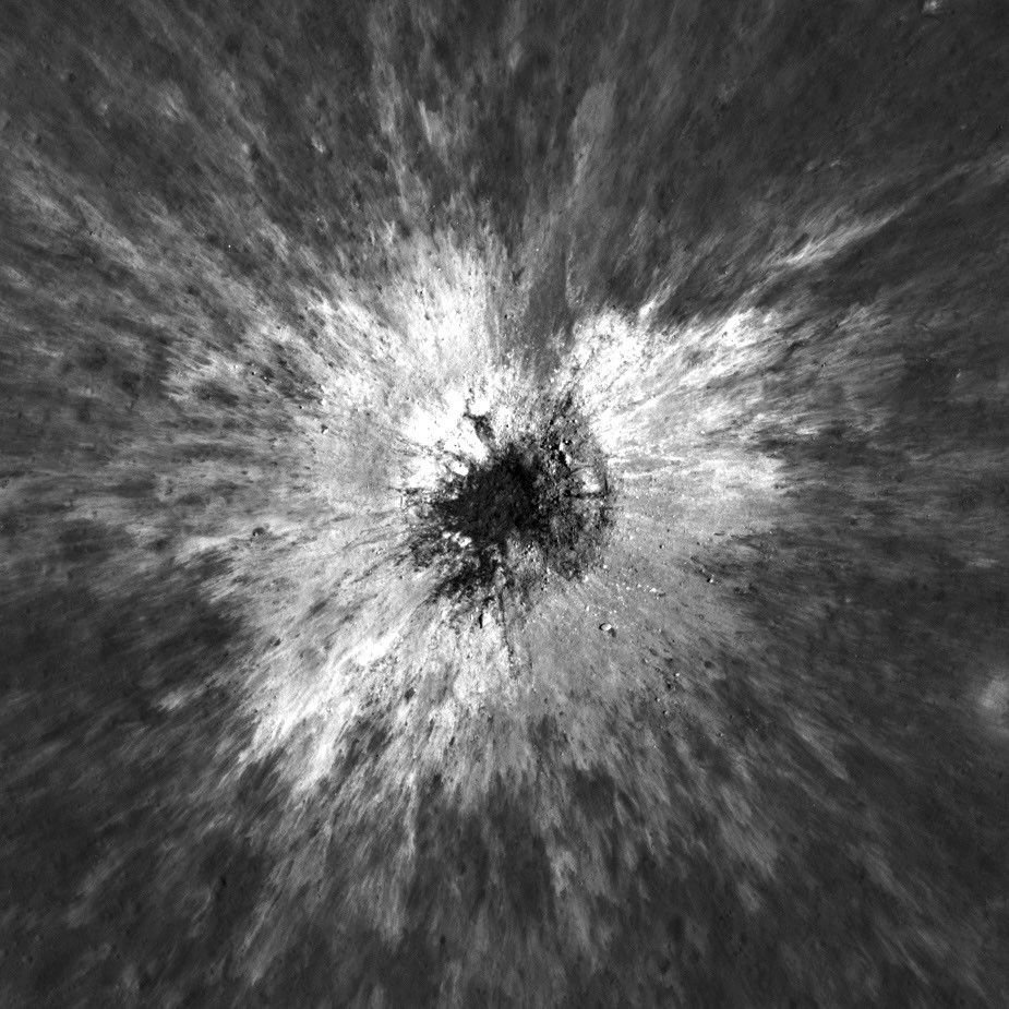 An image of the lunar surface with a large depression at the center surrounded by raised ridges that slope down back to the surface.