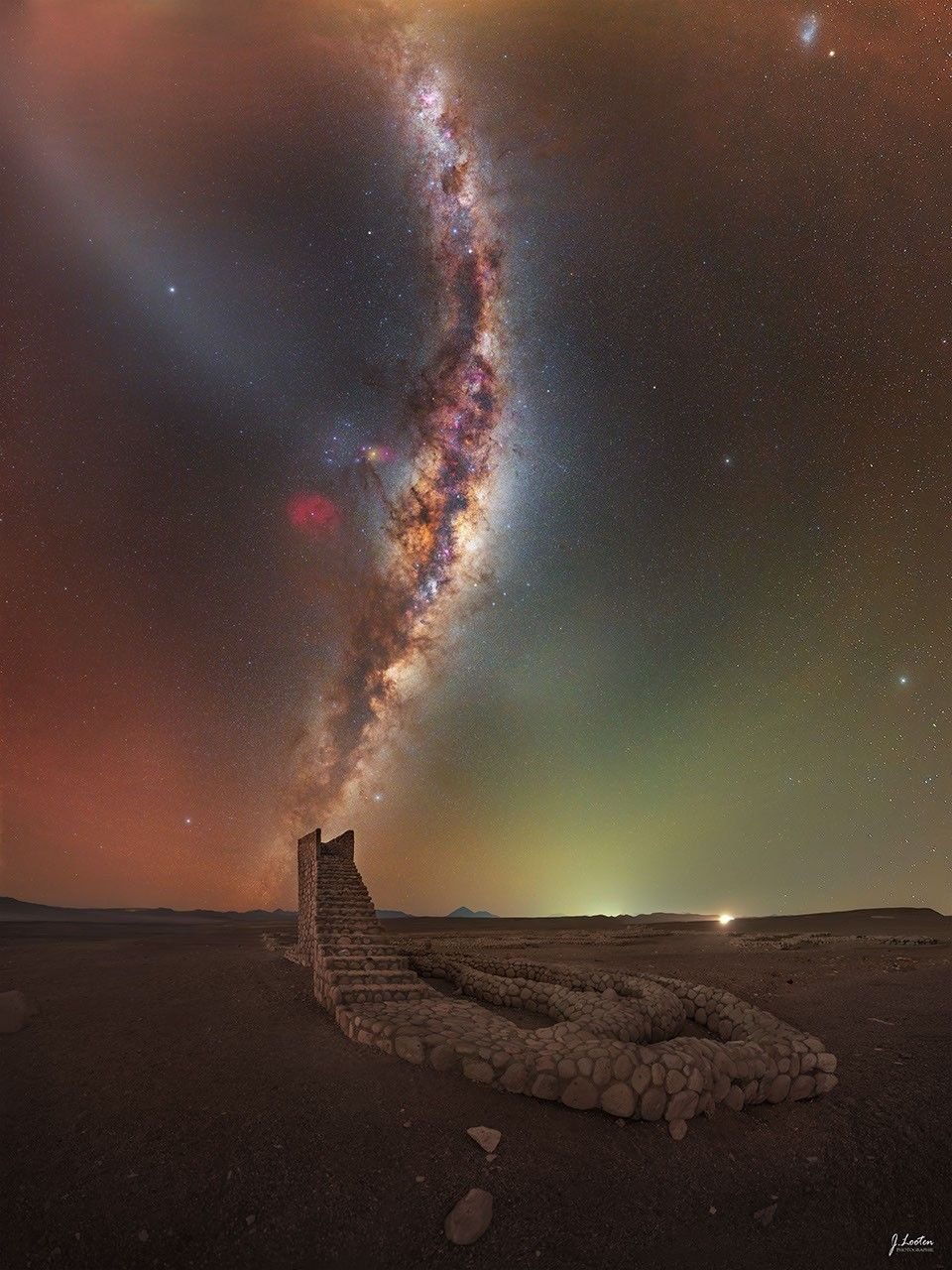 The Milky Way galaxy rises from the horizon and curves upward in the sky. In the foreground, a rock pathway is seen that culminates in a staircase that ends abruptly. The Milky Way band appears to be a continuation of the staircase. Please see the explanation for more detailed information.