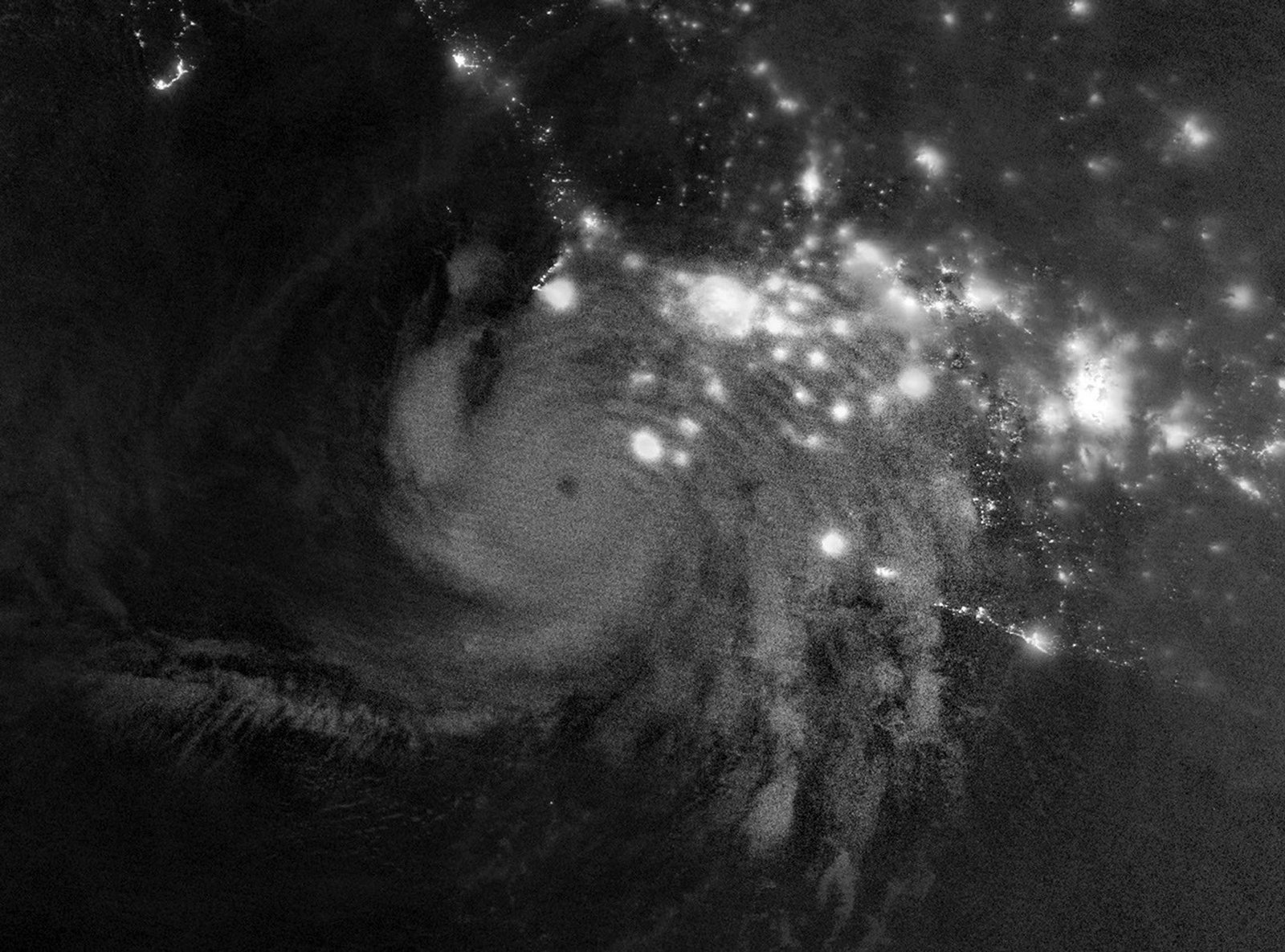 Gravity waves in the upper atmosphere appear as a semicircle of ripples in a nighttime, grayscale satellite image. Hurricane clouds and city lights in Mexico are also visible.